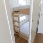 Compact bunk bed room with built-in wooden bunks, bright white interior, and modern minimalist styling.