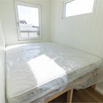 Double bedroom interior with large bed, bright windows, and clean contemporary floating shepherd’s hut design.