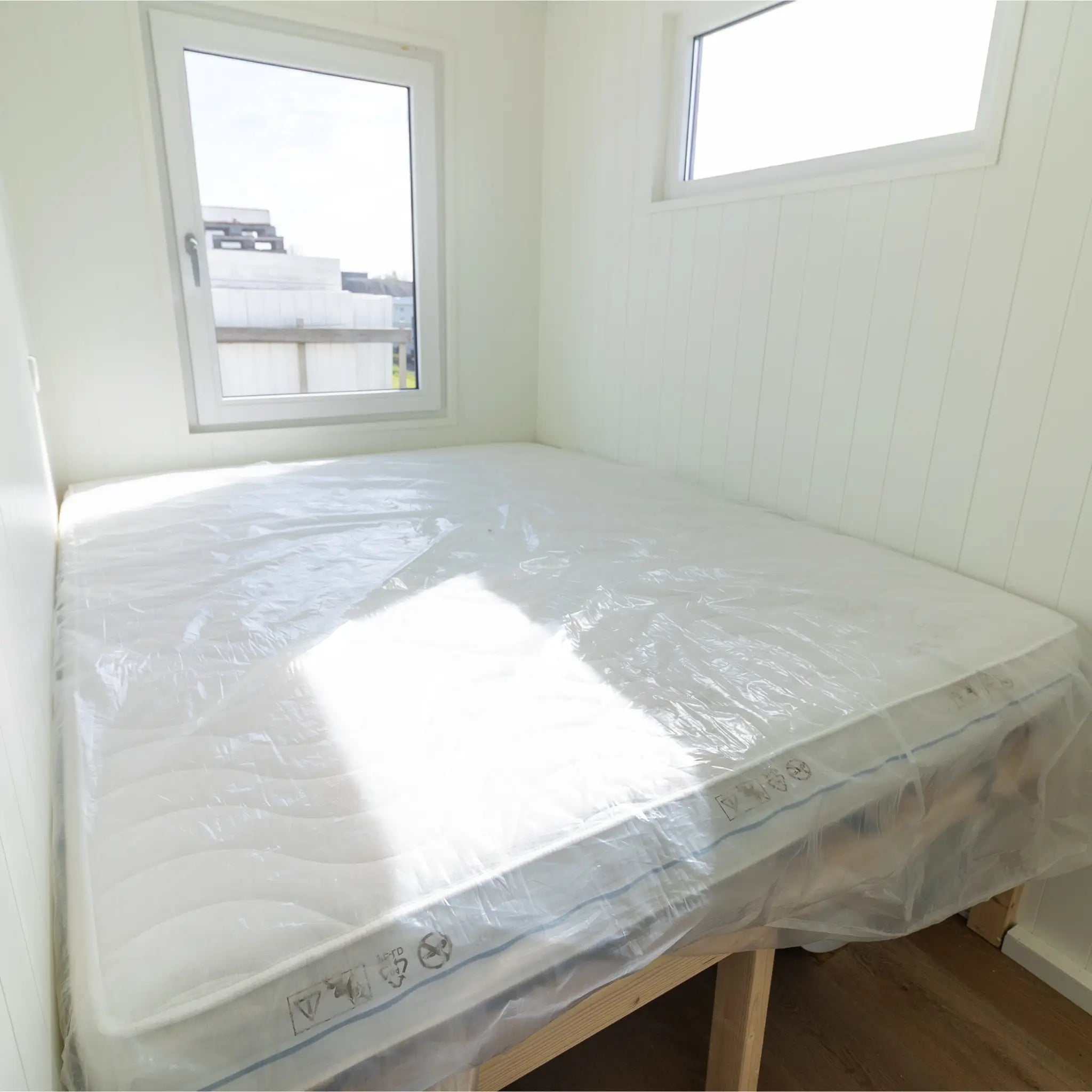 Double bedroom interior with large bed, bright windows, and clean contemporary floating shepherd’s hut design.