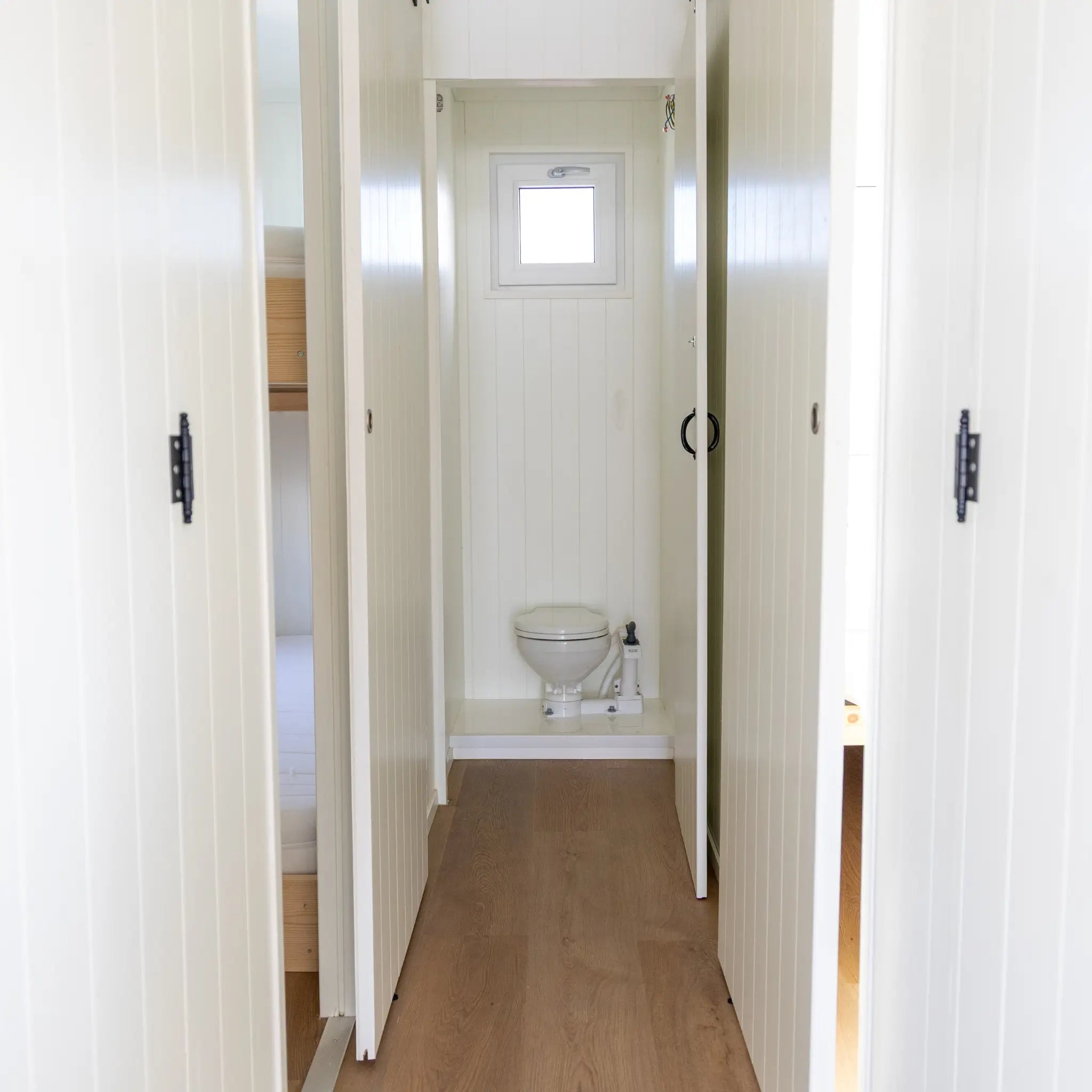 Interior hallway with sliding doors, wood-effect flooring, and compact WC access in modern floating shepherd’s hut.
