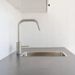 Modern kitchenette with stainless steel sink, minimalist cabinetry, and compact floating shepherd’s hut interior.