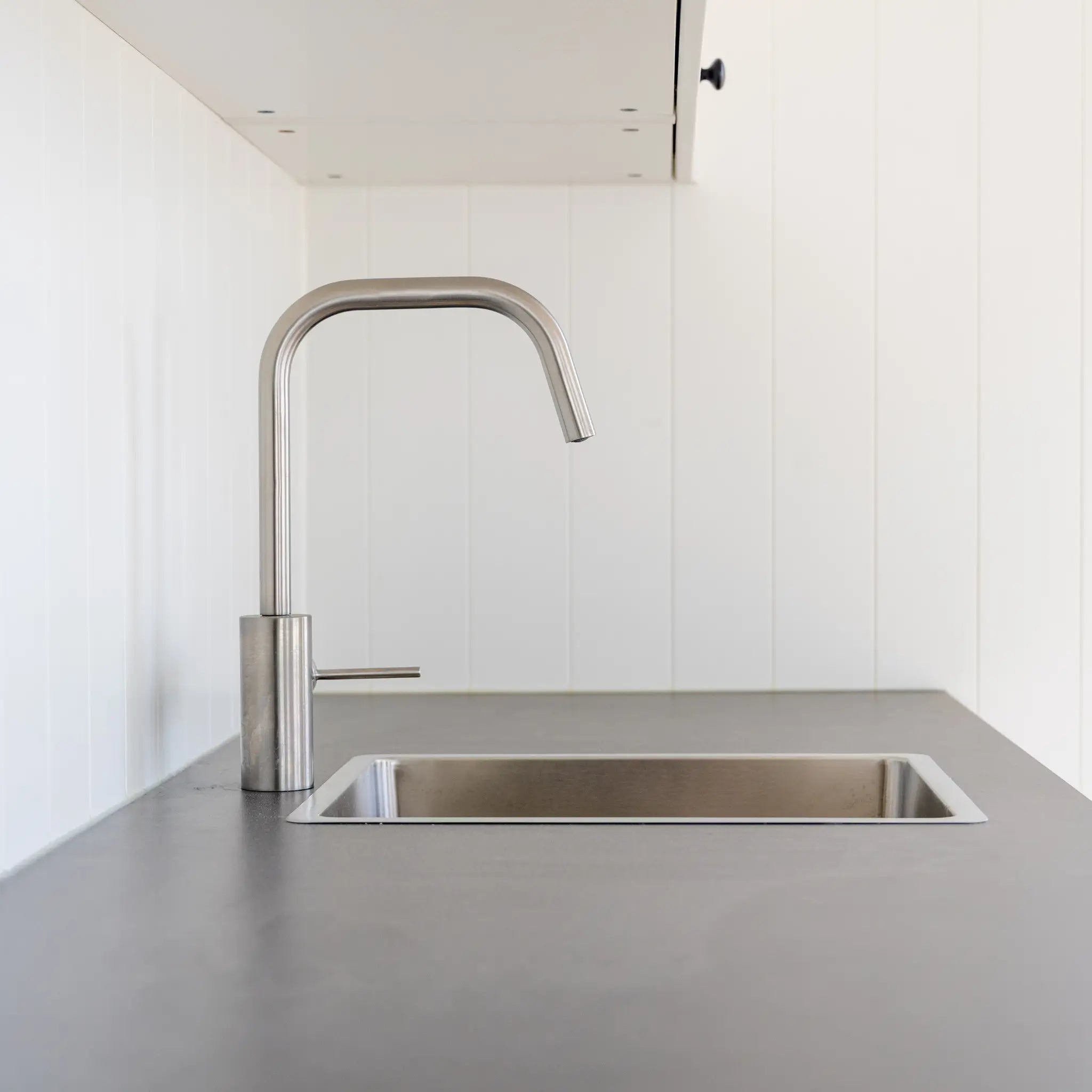 Modern kitchenette with stainless steel sink, minimalist cabinetry, and compact floating shepherd’s hut interior.
