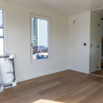 Bright open living space with modern windows, compact kitchenette, and contemporary floating shepherd’s hut layout.