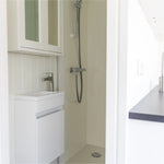 Compact shower room with modern vanity sink, glass shower enclosure, and bright contemporary interior.
