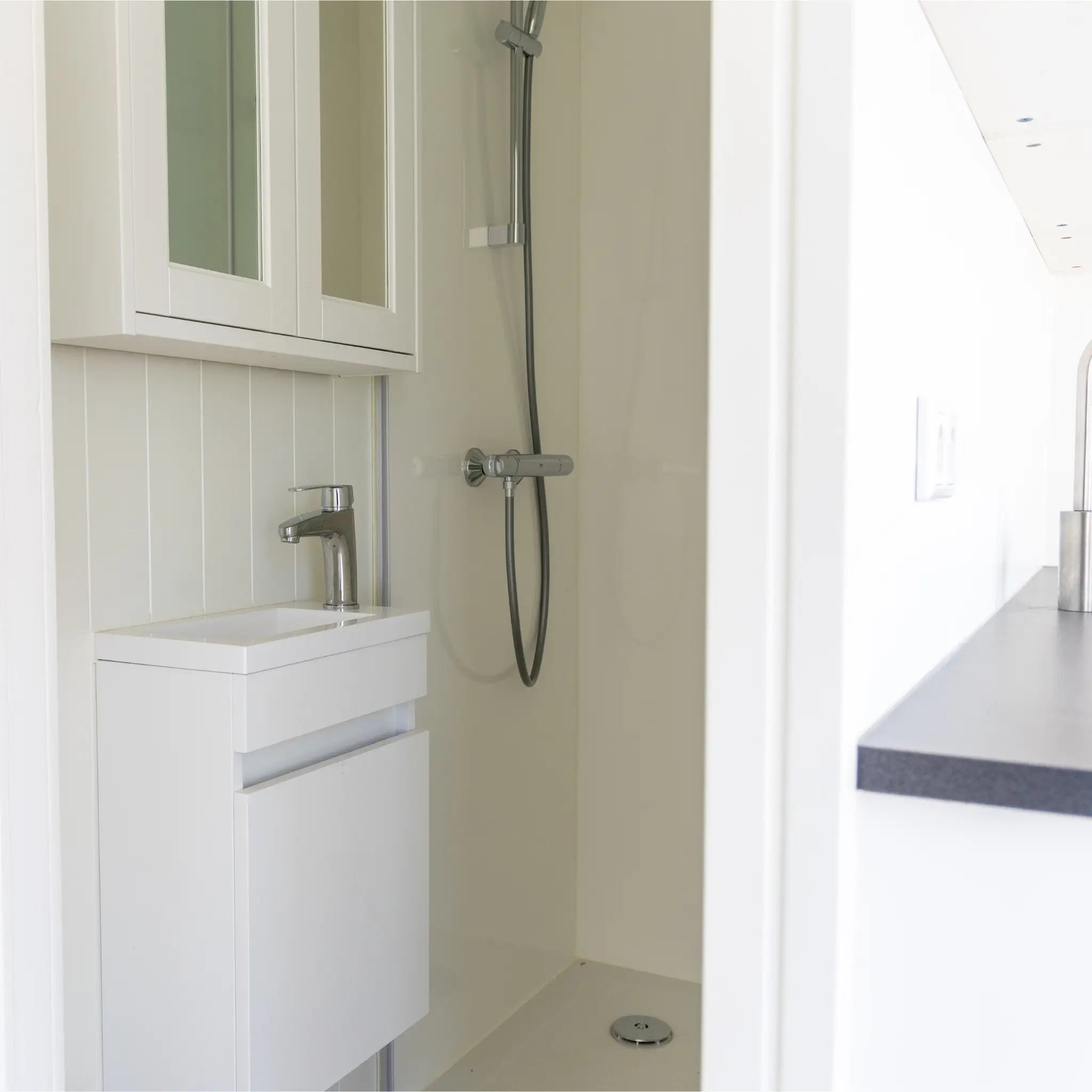 Compact shower room with modern vanity sink, glass shower enclosure, and bright contemporary interior.