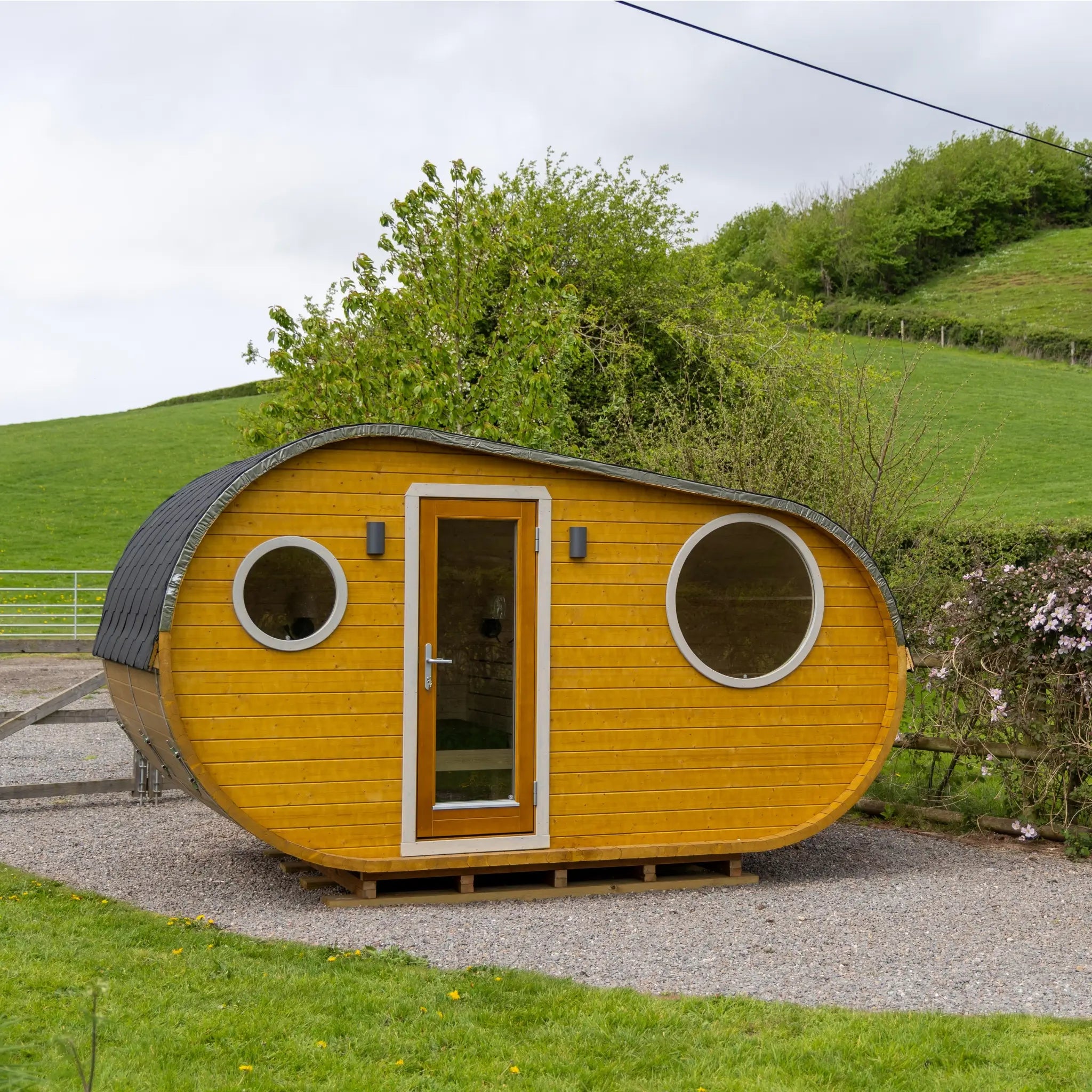 Full front view of Grotto glamping pod showcasing curved structure, circular windows and entrance