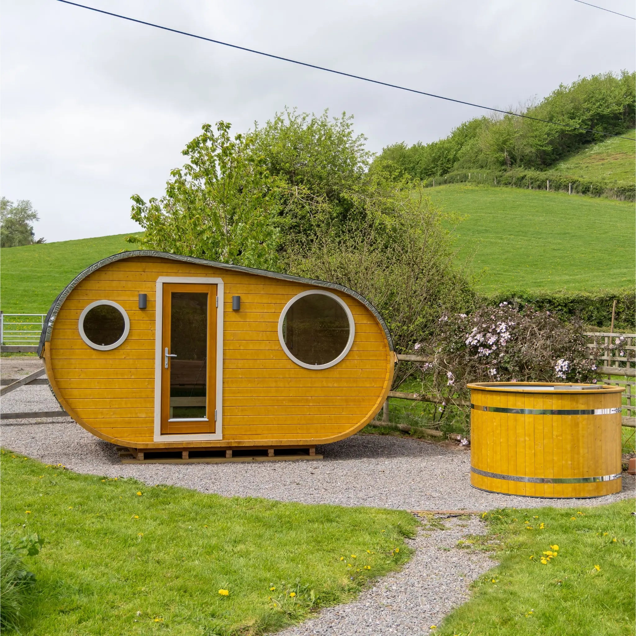 Front view of Grotto glamping pod with outdoor hot tub set in countryside location