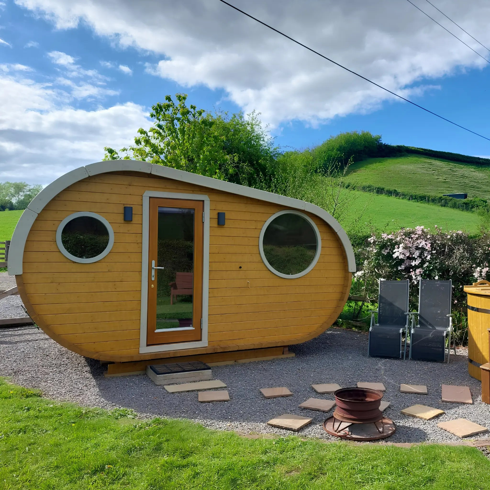 Front exterior of a luxury 3 person timber glamping pod with circular feature windows