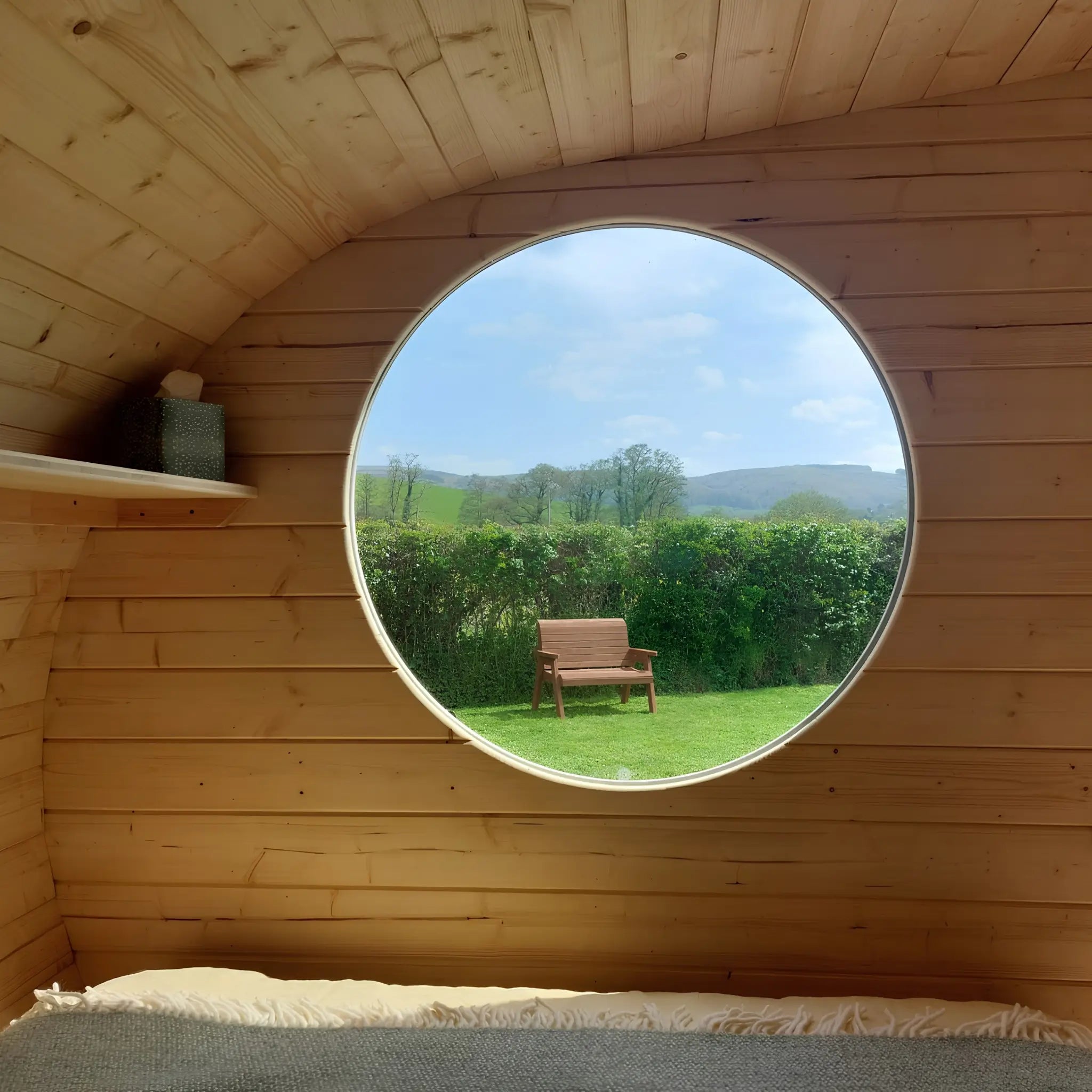 Large circular feature window inside a luxury 3 person glamping pod bedroom