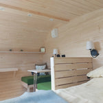 Double bed and convertible seating area inside a luxury timber glamping pod
