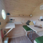 Wall-mounted table and convertible seating area inside a luxury 3 person glamping pod