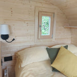 Double bed positioned beneath circular feature window inside a luxury glamping pod