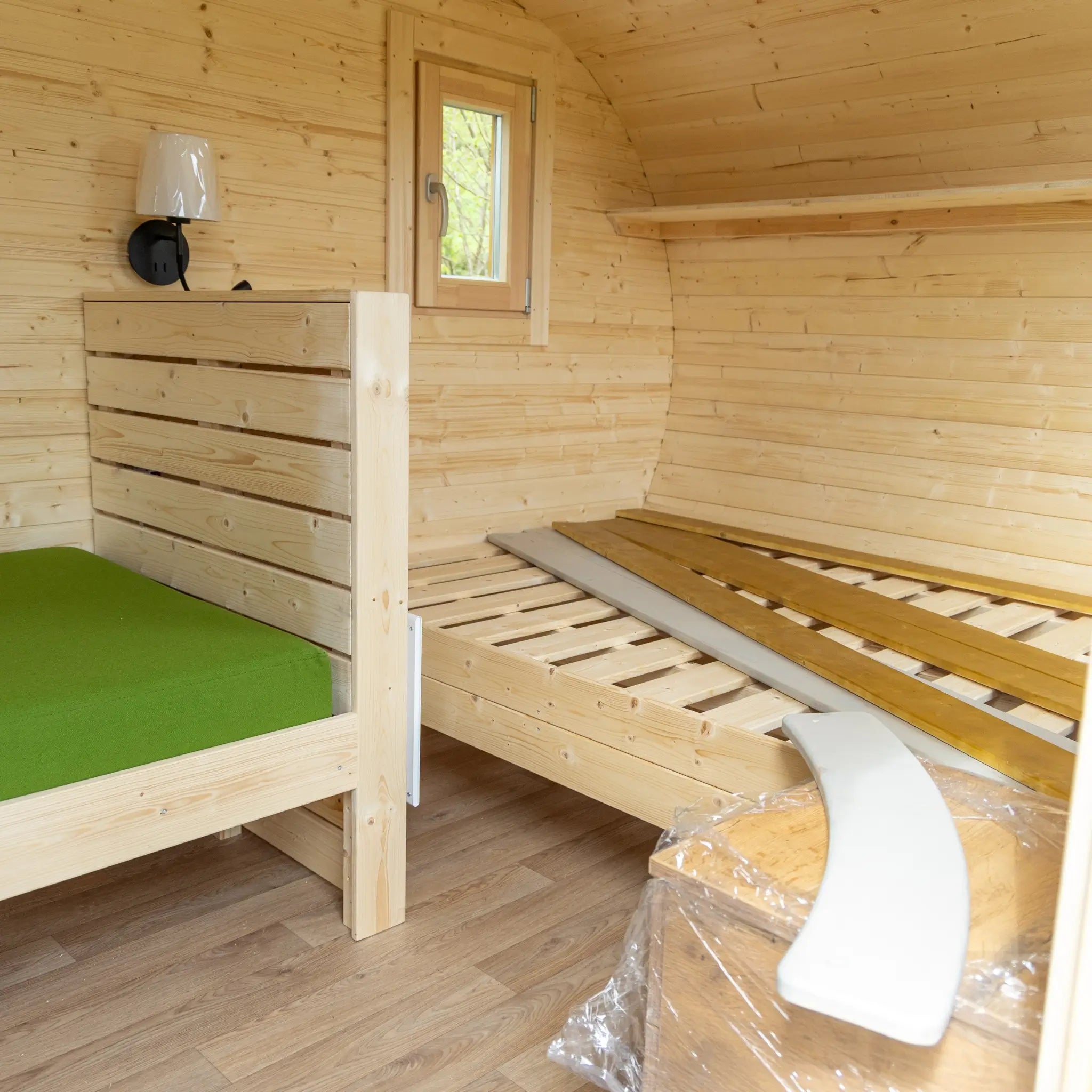 Interior view of Grotto glamping pod with double bed frame and convertible seating area