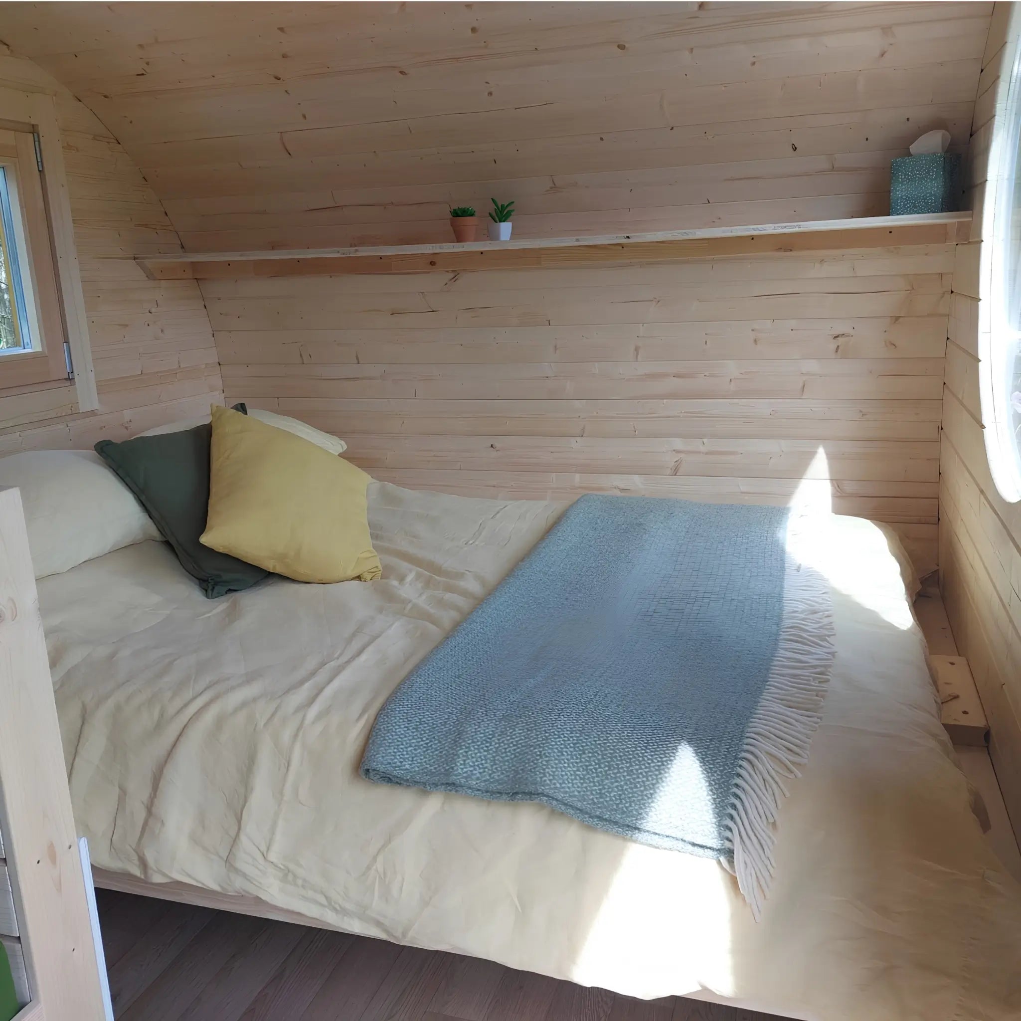 Double bed with luxury bedding inside a 3 person timber glamping pod bedroom