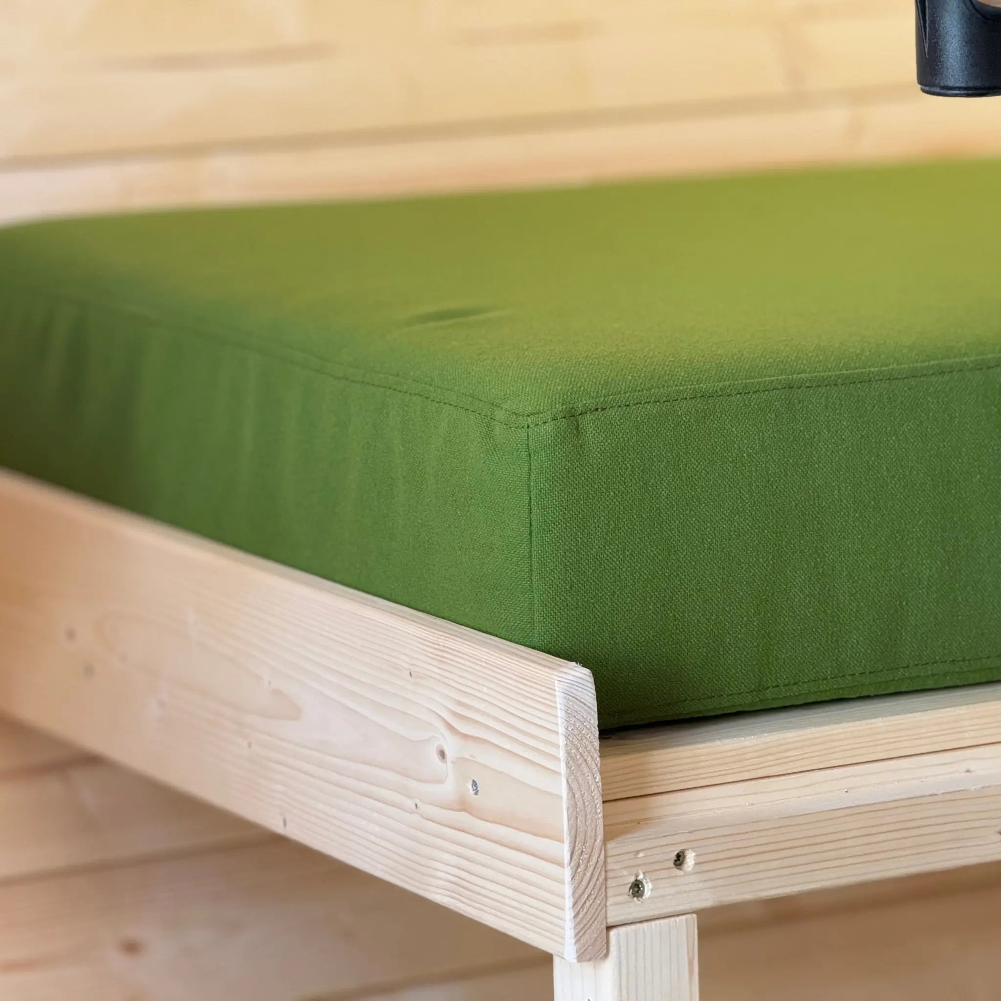 Close-up of green cushion mattress on convertible bed in Grotto glamping pod