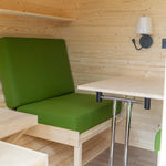 Convertible seating with green cushions and backrest in Grotto 3 person glamping pod interior