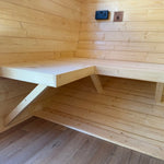 Wall-mounted wooden bench inside Grotto glamping pod showing space-saving interior design