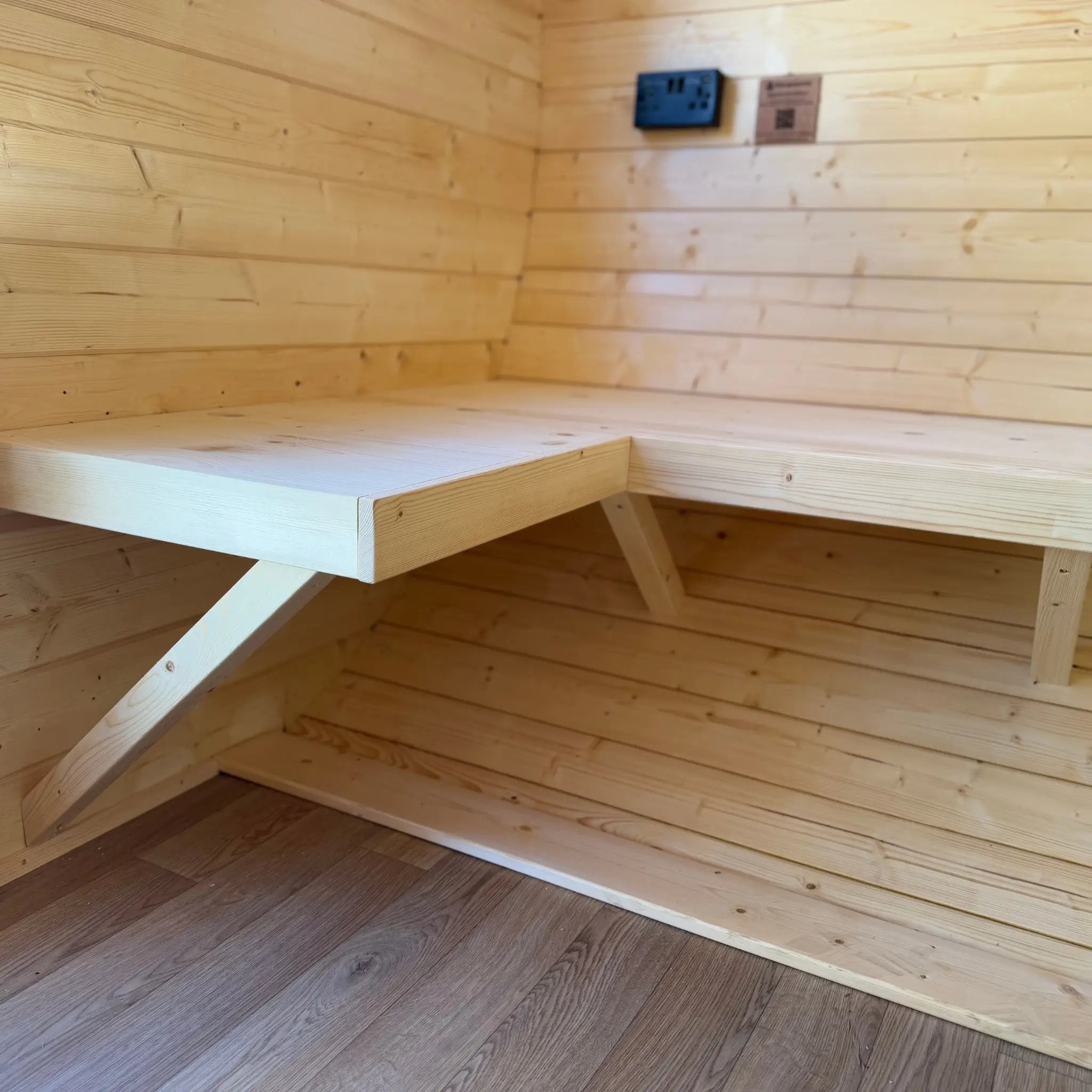 Wall-mounted wooden bench inside Grotto glamping pod showing space-saving interior design