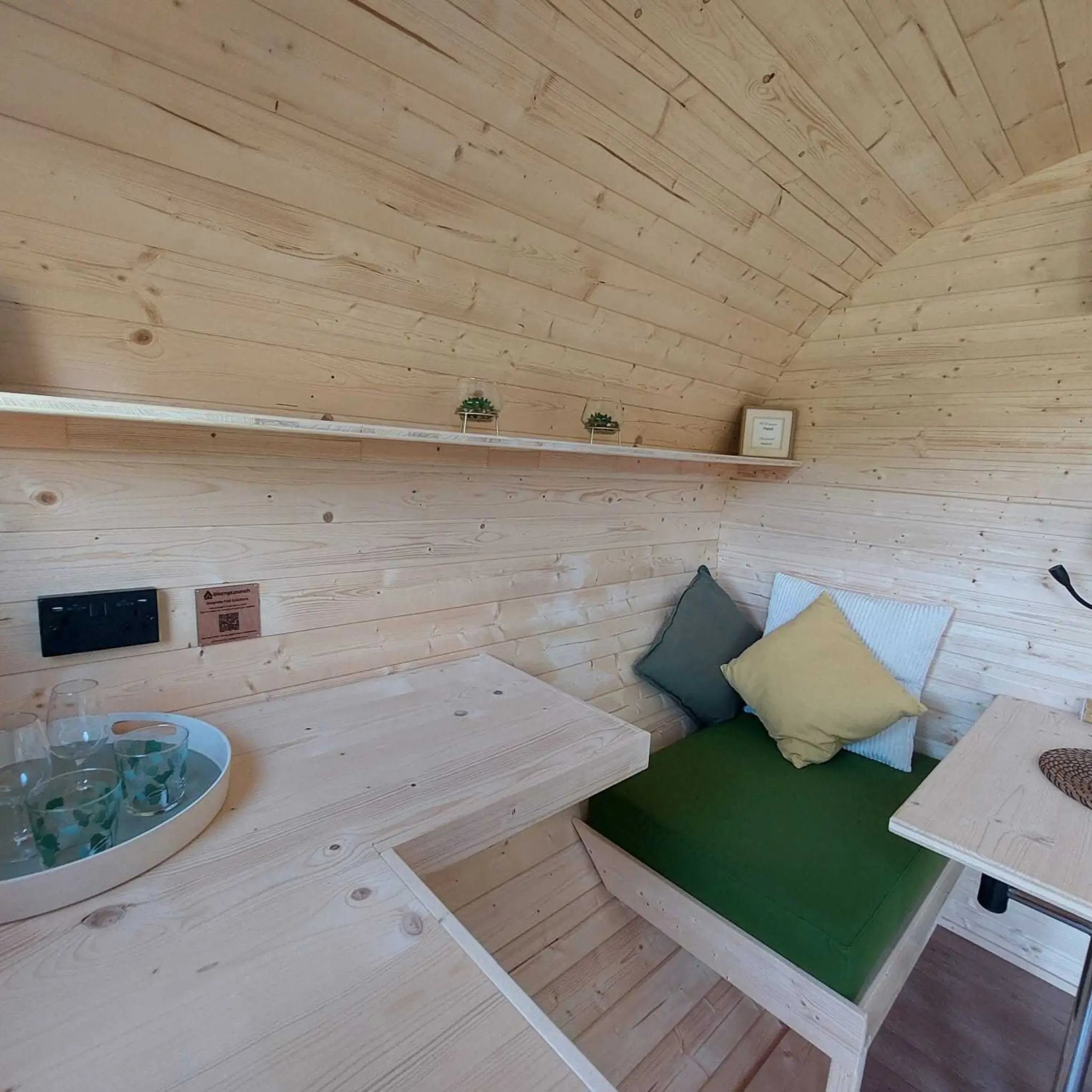 Wall-mounted preparation table beside convertible seating inside a luxury glamping pod