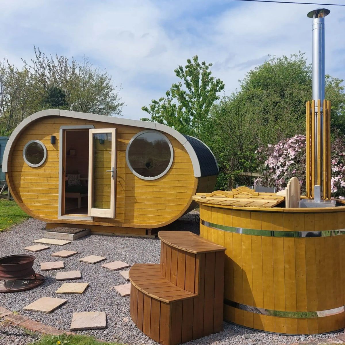 The Grotto luxury 3 person glamping pod with timber exterior, circular windows and outdoor wood-fired hot tub.