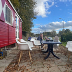 Side view of The Hawthorne shepherds hut beside outdoor patio seating area, showcasing countryside glamping accommodation design.