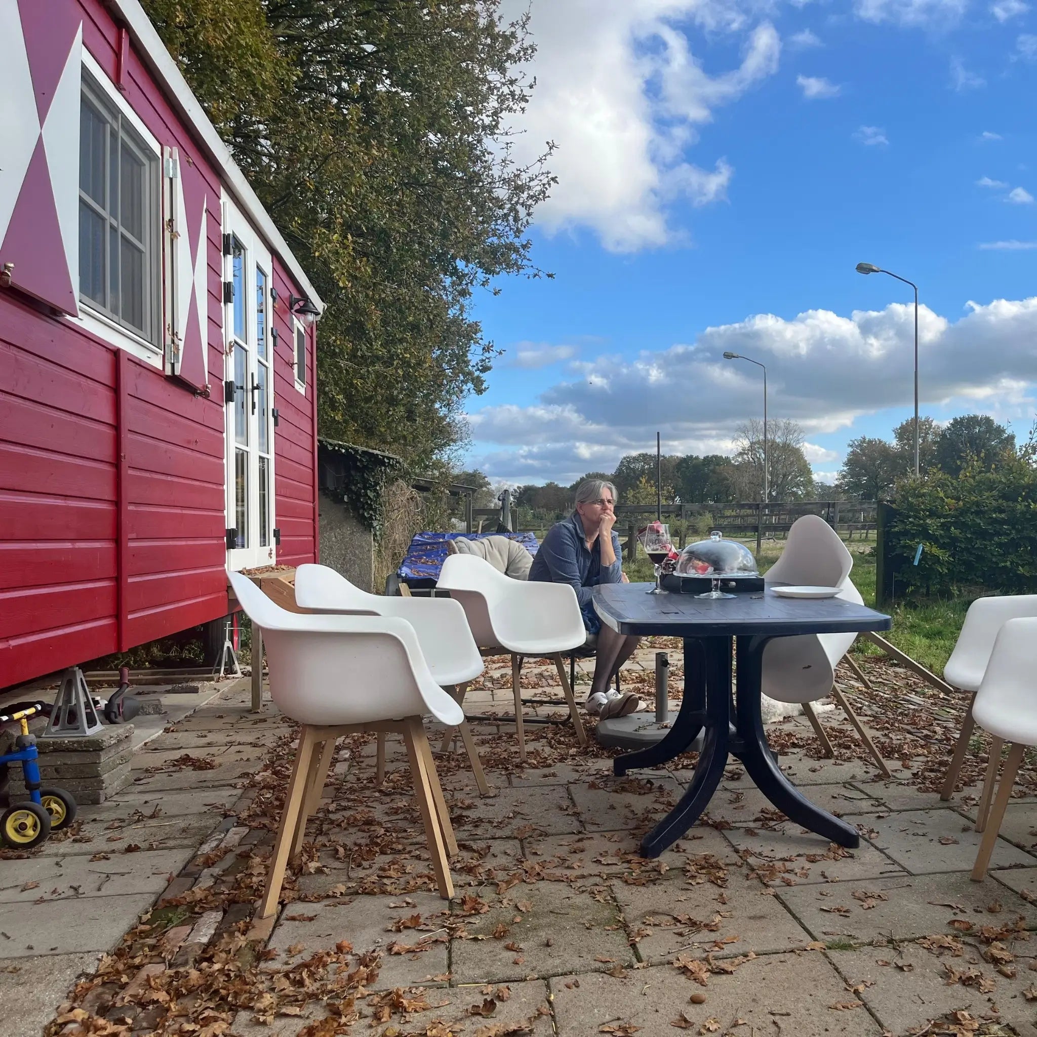 Side view of The Hawthorne shepherds hut beside outdoor patio seating area, showcasing countryside glamping accommodation design.