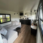 Open layout interior of The Hawthorne shepherds hut showing living area, kitchenette and bright contemporary design.