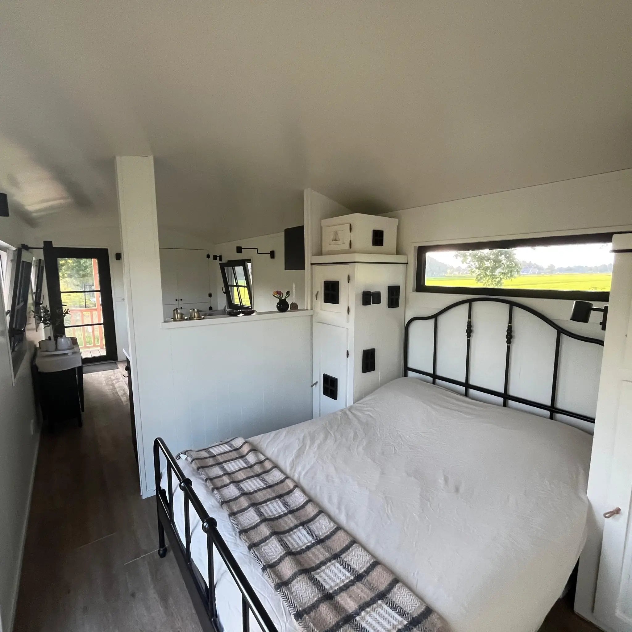 Open-plan interior view from sleeping area in The Hawthorne shepherds hut featuring kitchen, lounge and luxury compact living design.