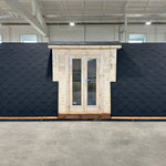 Front exterior view of the Hearthwood luxury 2–4 person glamping pod with timber entrance and black shingle curved roof