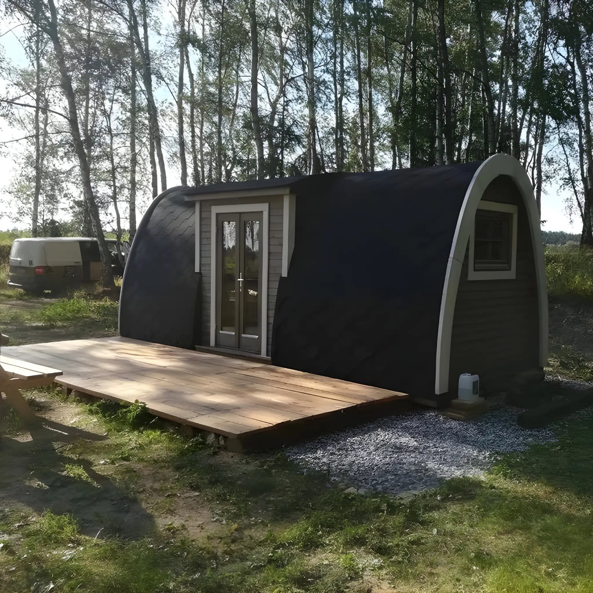 Hearthwood glamping pod installed in a garden setting with side elevation and surrounding greenery