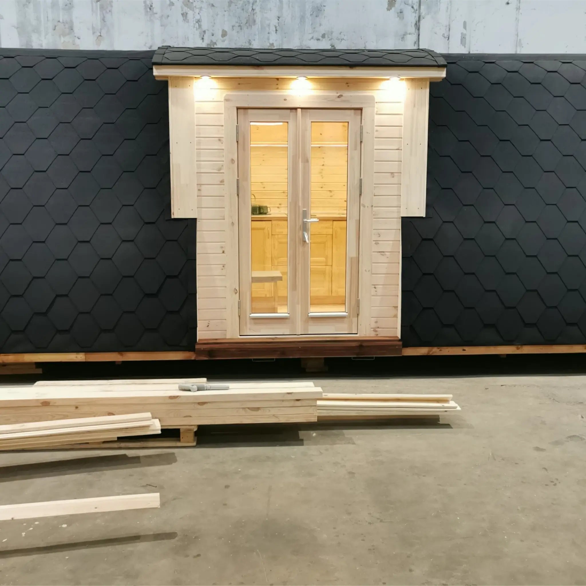 Full front exterior view of The Hearthwood Pod luxury 2 person glamping pod in workshop setting