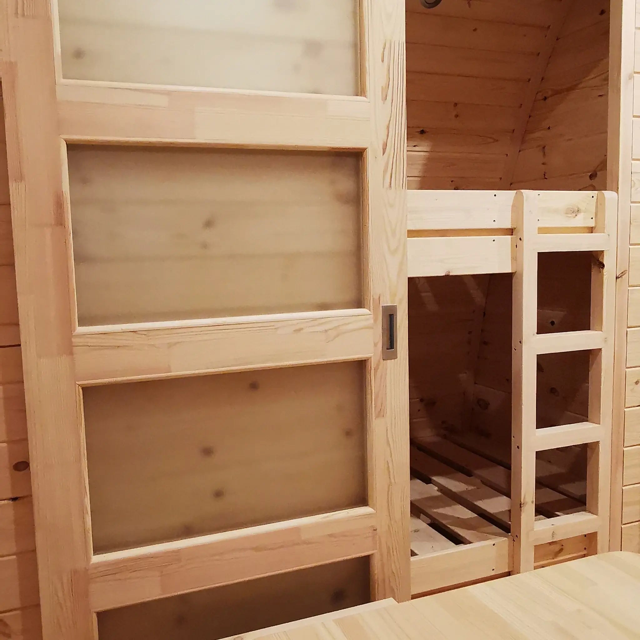 Interior bunk bed with sliding wooden door inside the Hearthwood luxury 6 person glamping pod