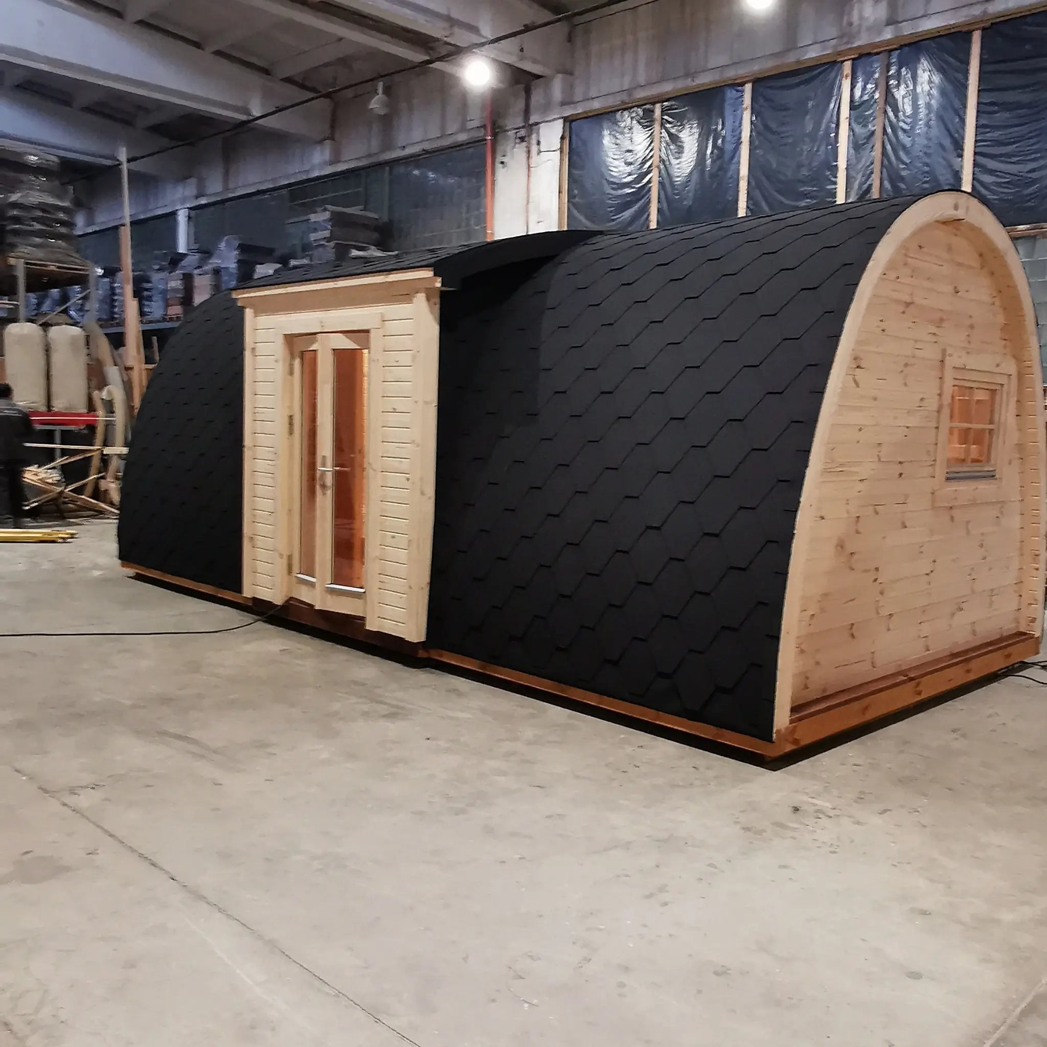 Side exterior view of the Hearthwood luxury 6 person glamping pod with black shingle curved roof