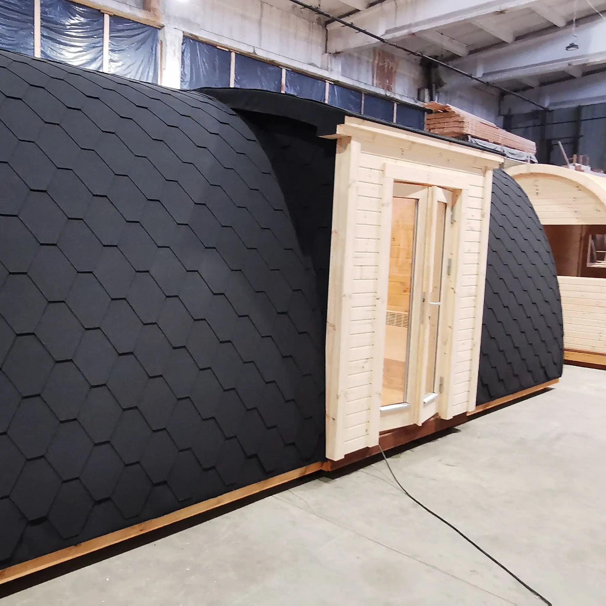 Alternate side exterior view of the Hearthwood luxury 6 person glamping pod with timber walls and shingle roof