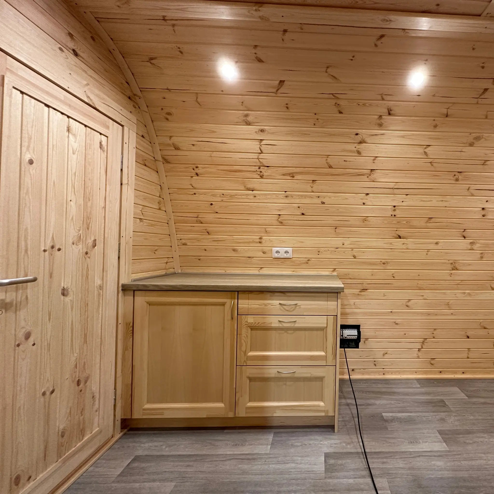 Timber kitchenette unit with drawers and worktop in the open-plan interior of The Hearthwood Pod glamping accommodation