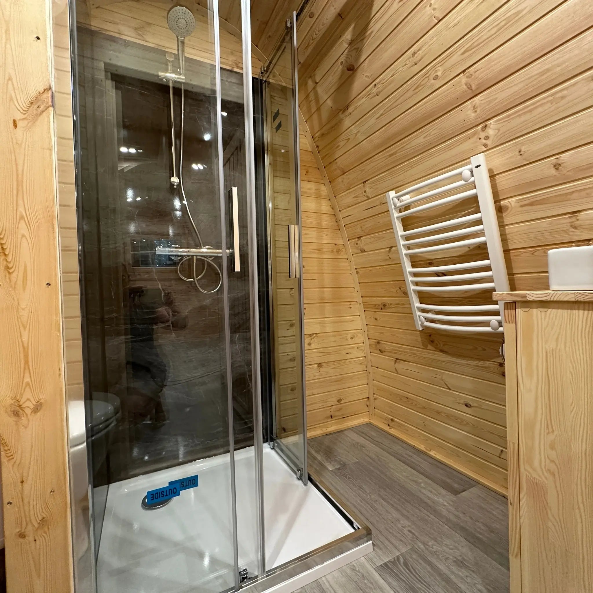 Compact bathroom with shower enclosure and heated towel rail inside The Hearthwood Pod luxury glamping pod