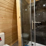 Close-up of glass shower enclosure with modern fittings in The Hearthwood Pod luxury 6 person glamping pod