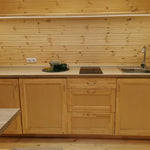 Luxury glamping pod kitchenette with solid wood cabinets, induction hob, sink and timber interior finish