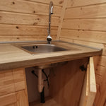 Compact stainless steel sink and mixer tap in luxury glamping pod kitchen with wooden interior walls