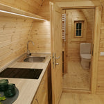 Luxury glamping pod interior showing kitchenette with induction hob and open bathroom door