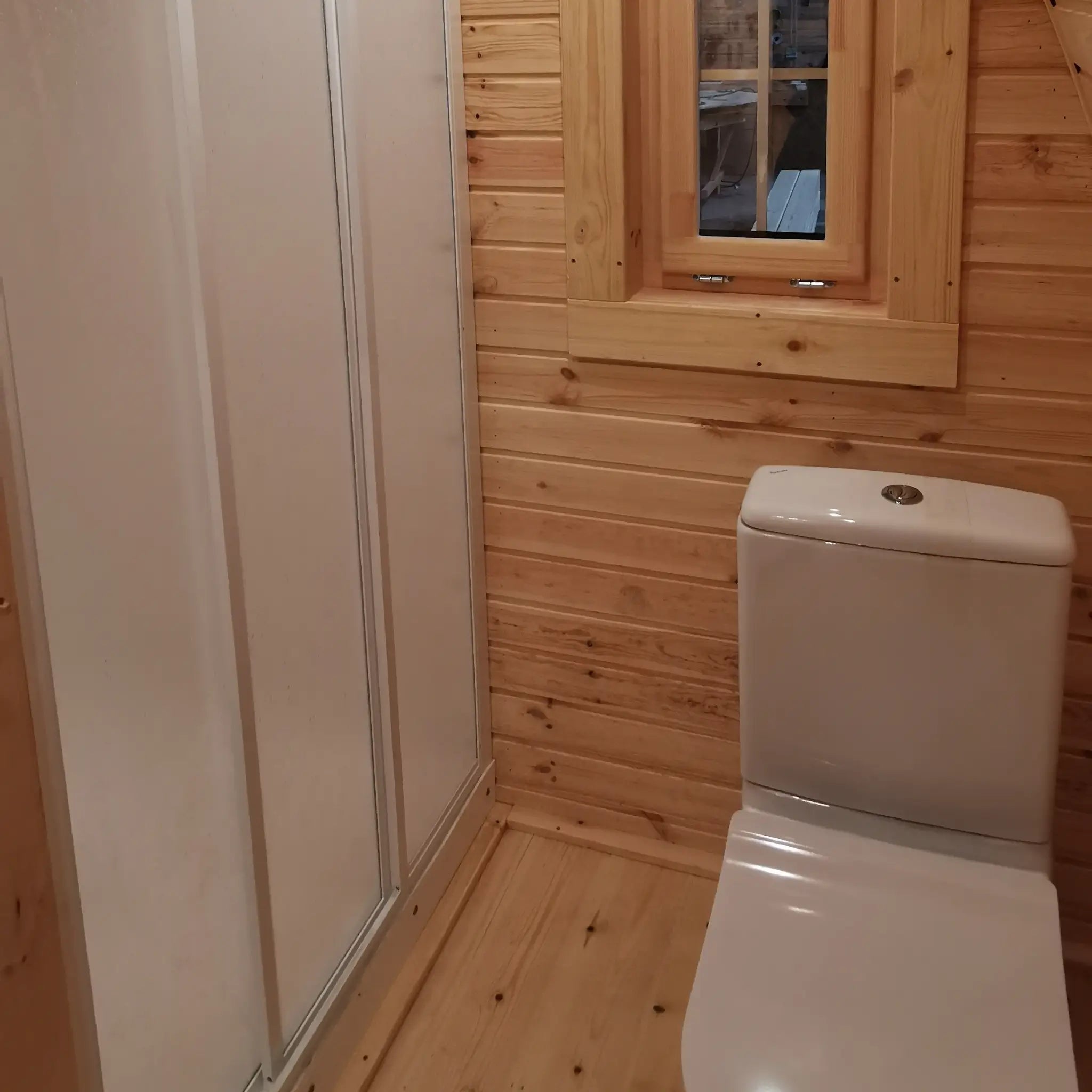 Luxury glamping pod bathroom with shower enclosure, toilet and timber-lined interior