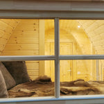 Interior view of the Hearthwood Pod luxury glamping pod seen through the window, highlighting the cosy sleeping space and natural timber finish.