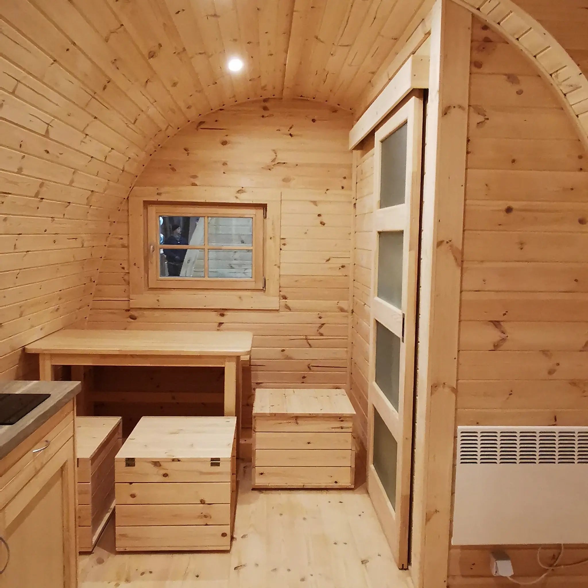 Interior view showing dining table, radiator, and bunk beds in The Hearthwood Pod luxury 6 person glamping accommodation