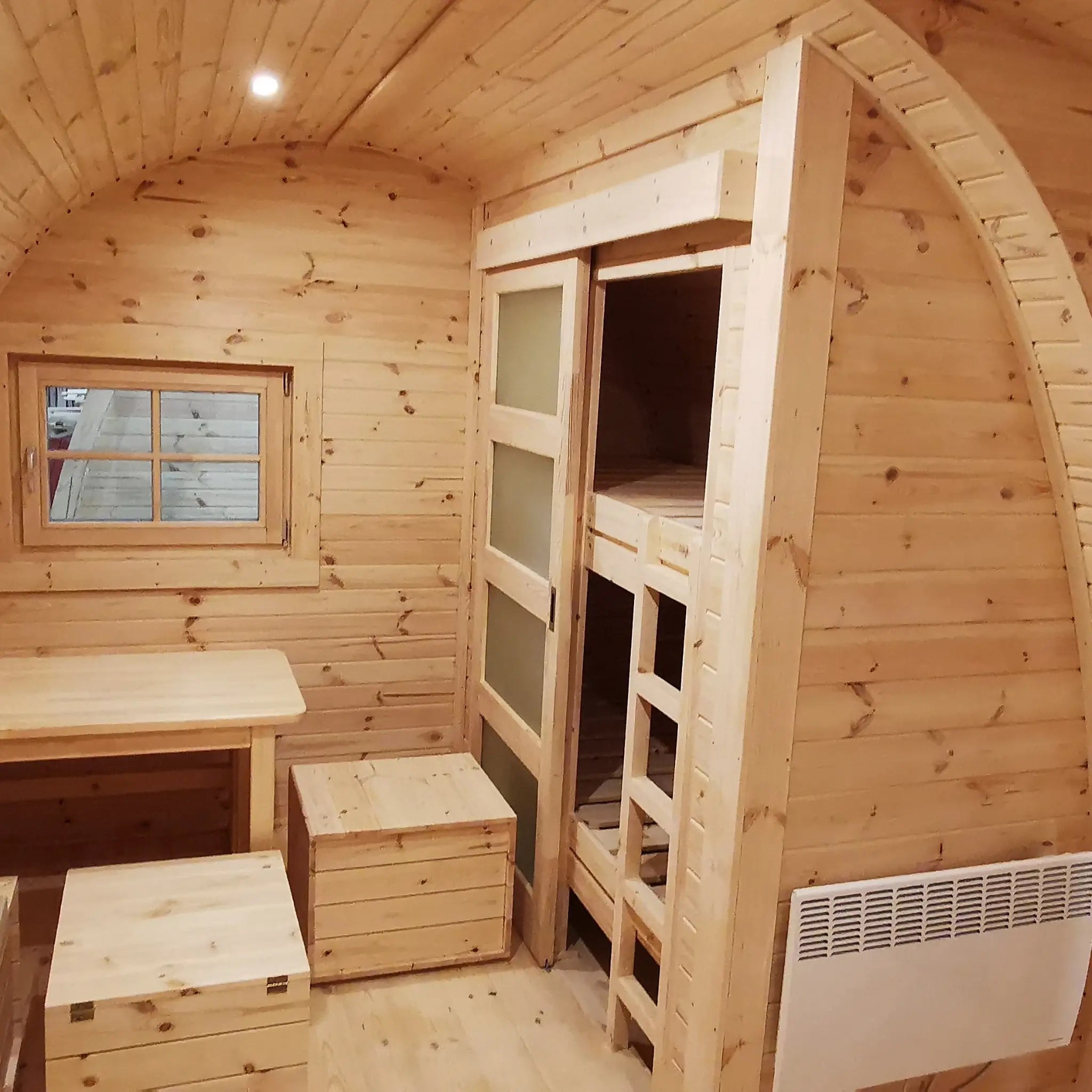 Open dining area with radiator and bunk beds in The Hearthwood Pod luxury 6 person glamping pod interior