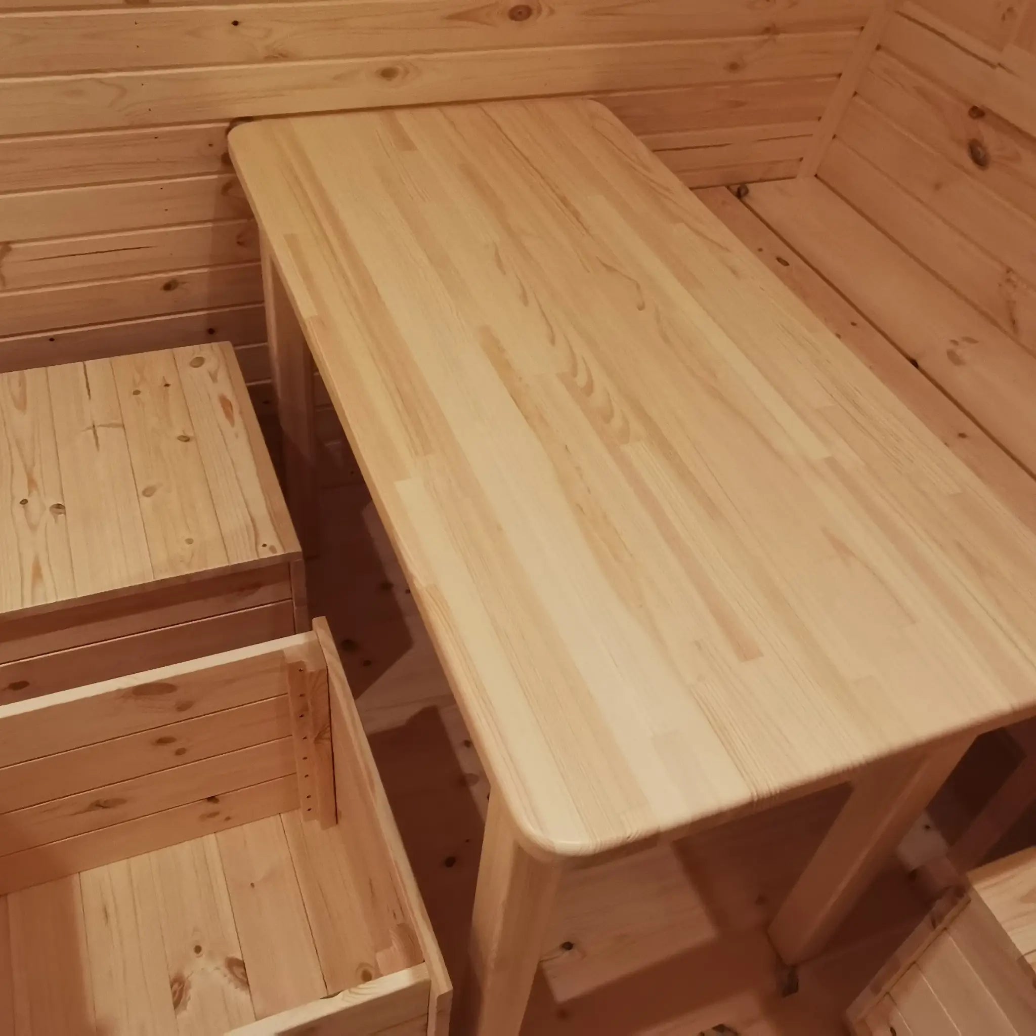 Wooden dining table with built-in storage seating inside The Hearthwood Pod luxury 6 person glamping pod