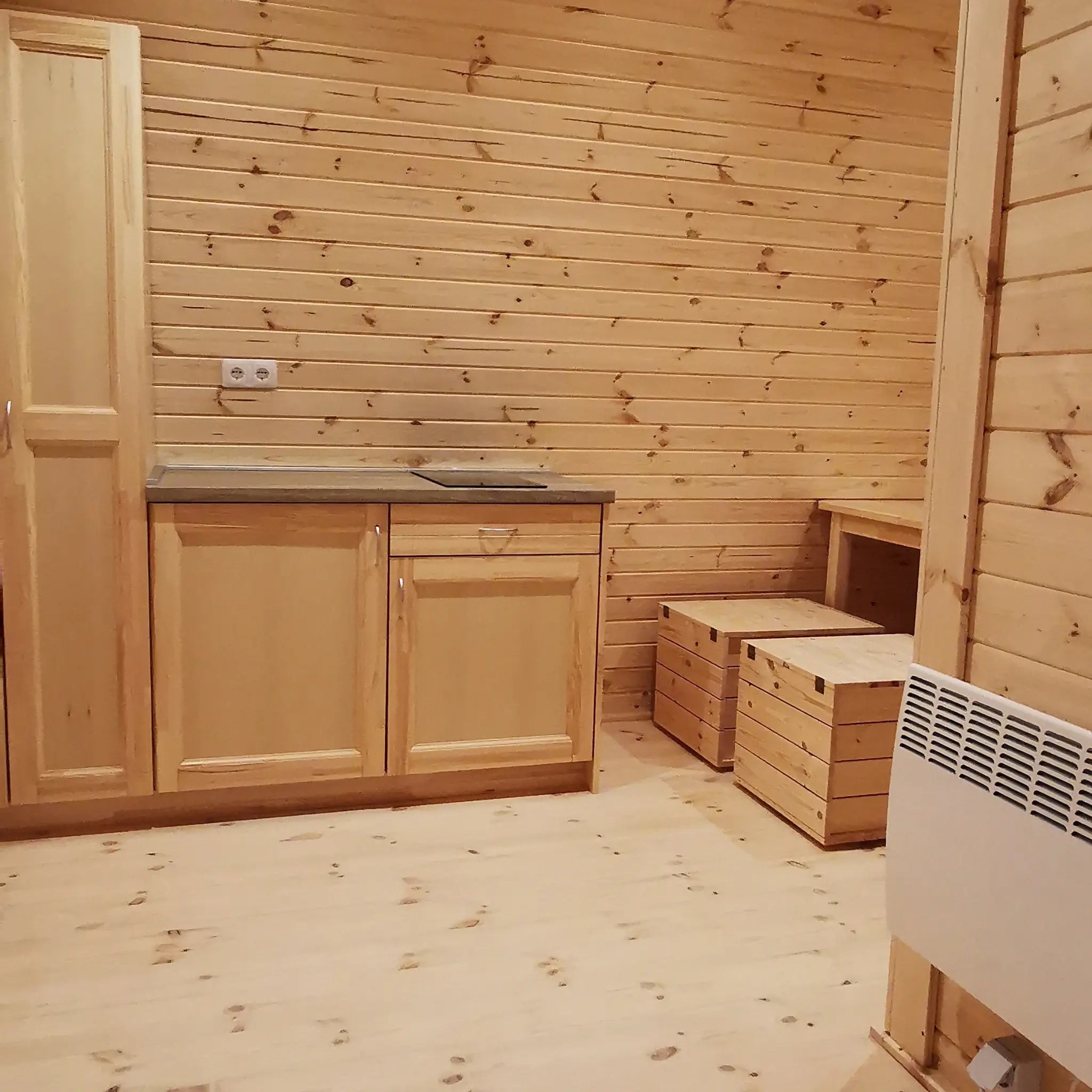 Curved timber interior featuring kitchenette, dining area, and compact radiator in the Hearthwood 6 berth glamping pod