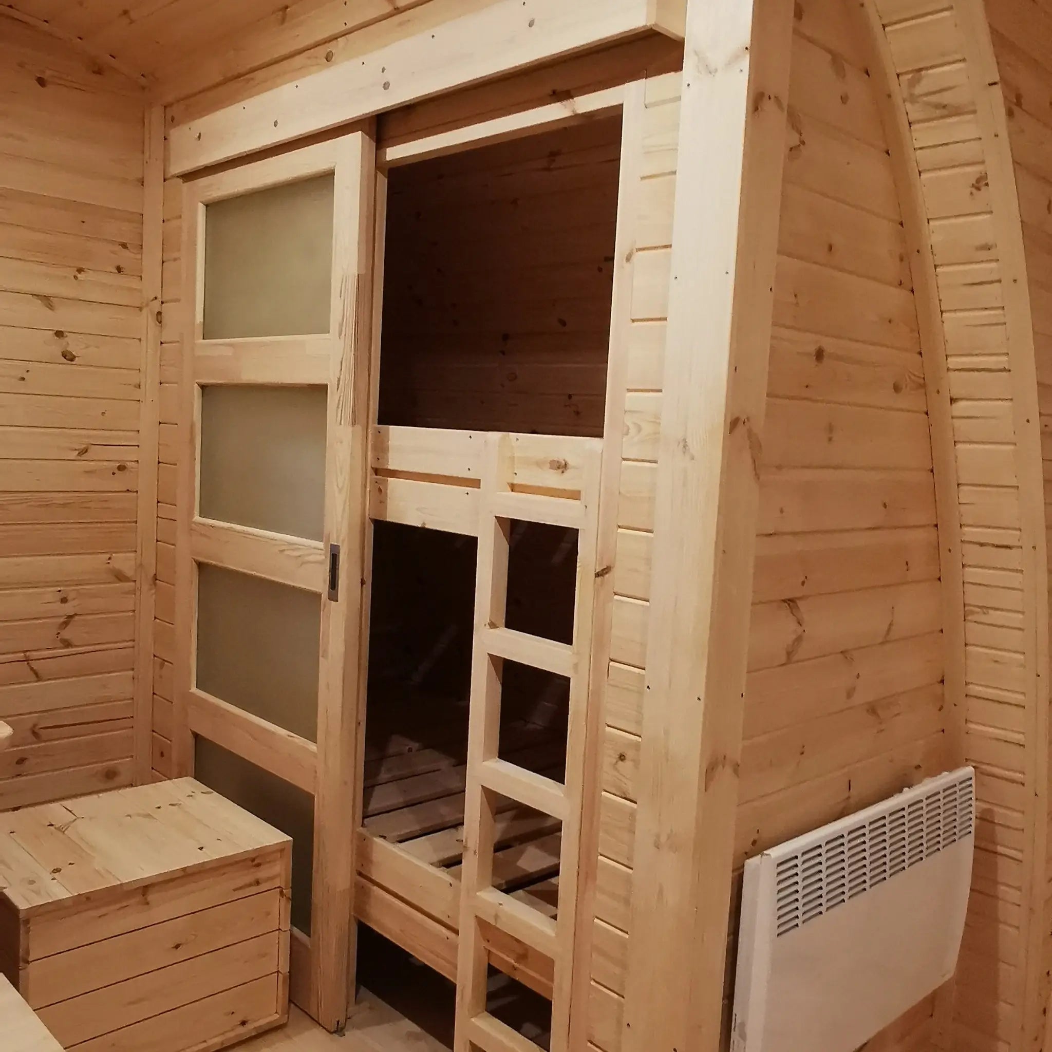Bunk bed sleeping area with radiator and timber walls inside the Hearthwood 6 person glamping pod
