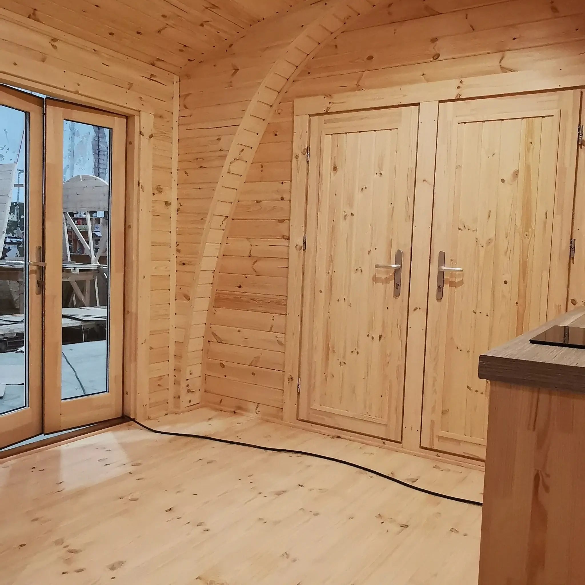 Central interior view with two bedroom entrances and natural wood finishes in the Hearthwood luxury glamping pod