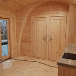 Interior view of double bedroom doors and kitchenette inside the Hearthwood Pod luxury 6 person glamping pod