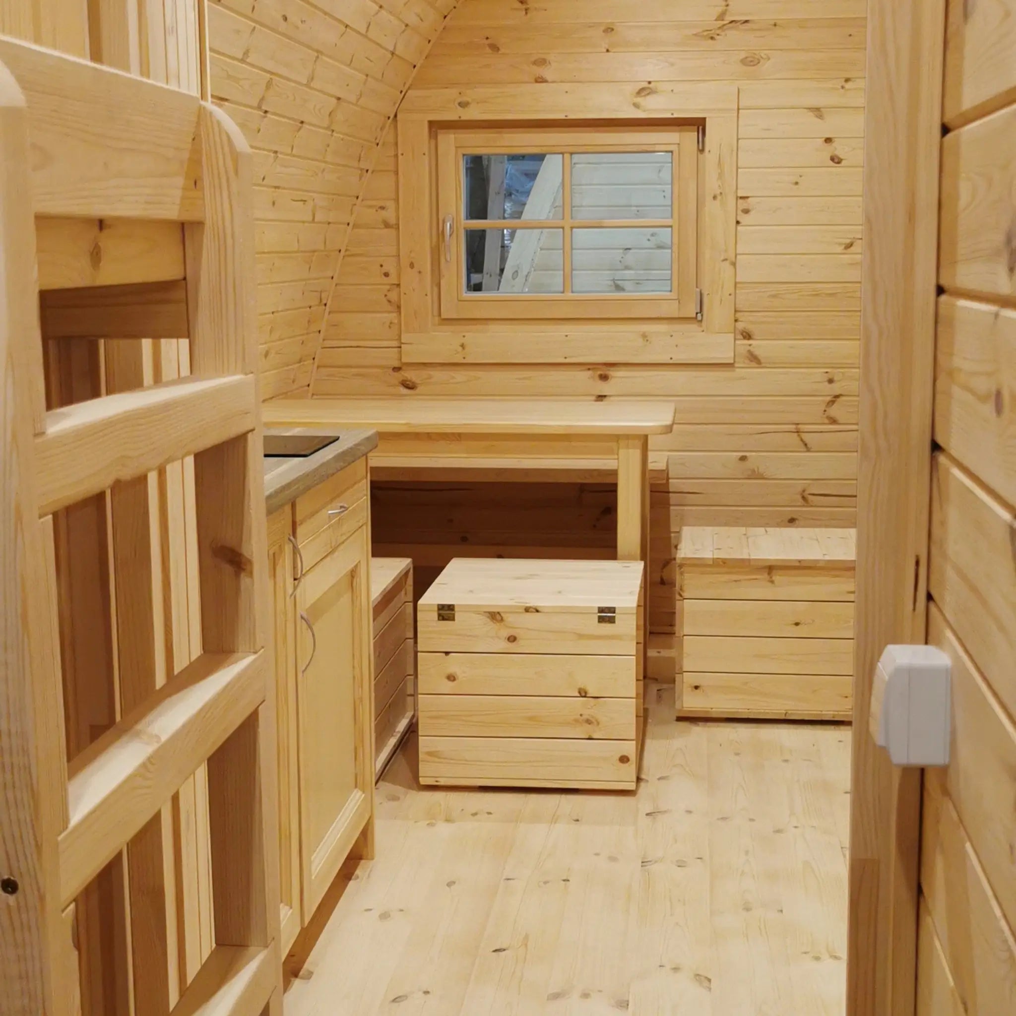 Close-up interior view from bunk bed room into dining space inside the Hearthwood Pod 6 person glamping pod